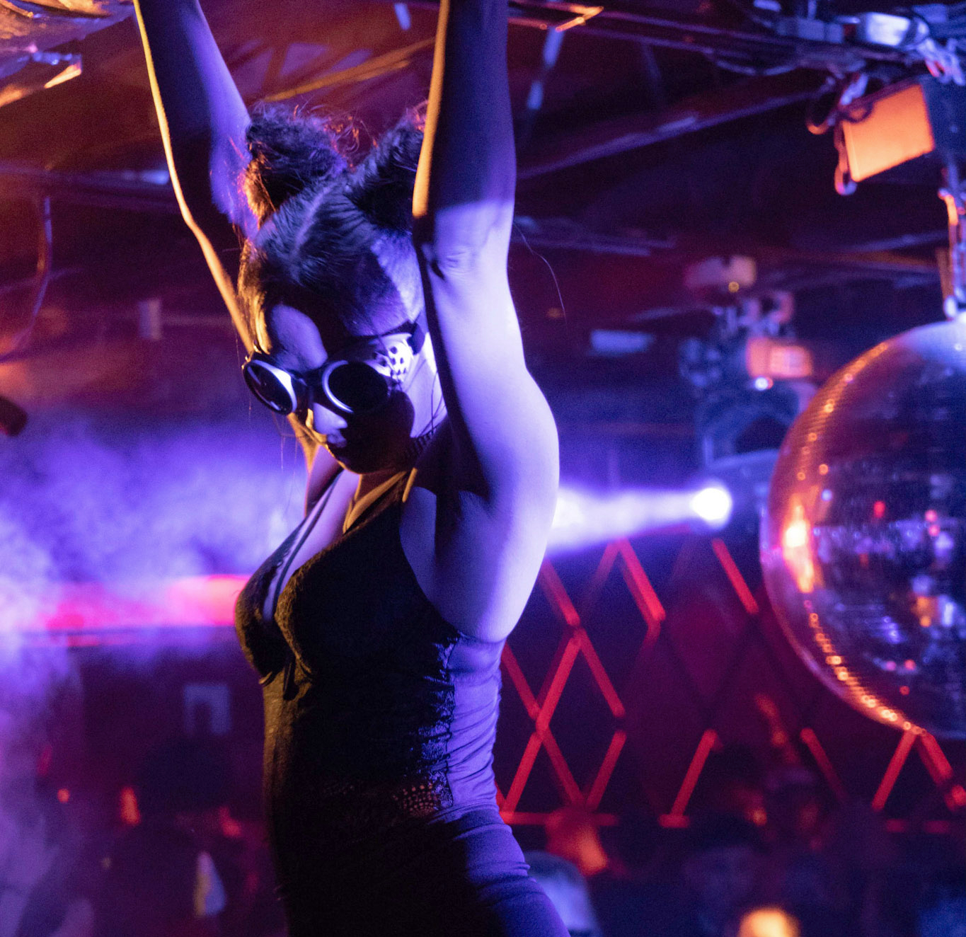 Girl dancing beside disco ball in a nightclub